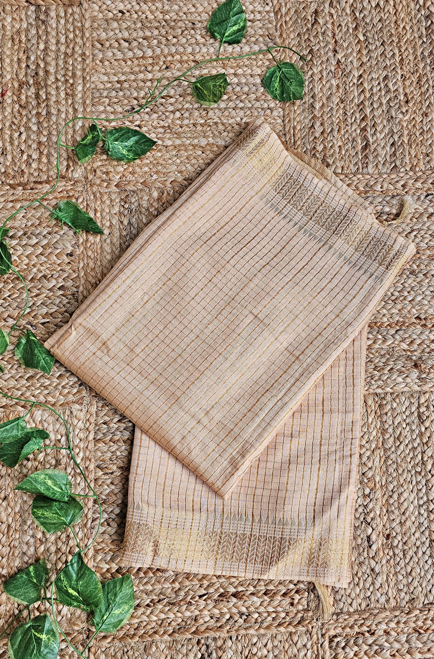 Two woven placemats on a textured surface with green leaves.