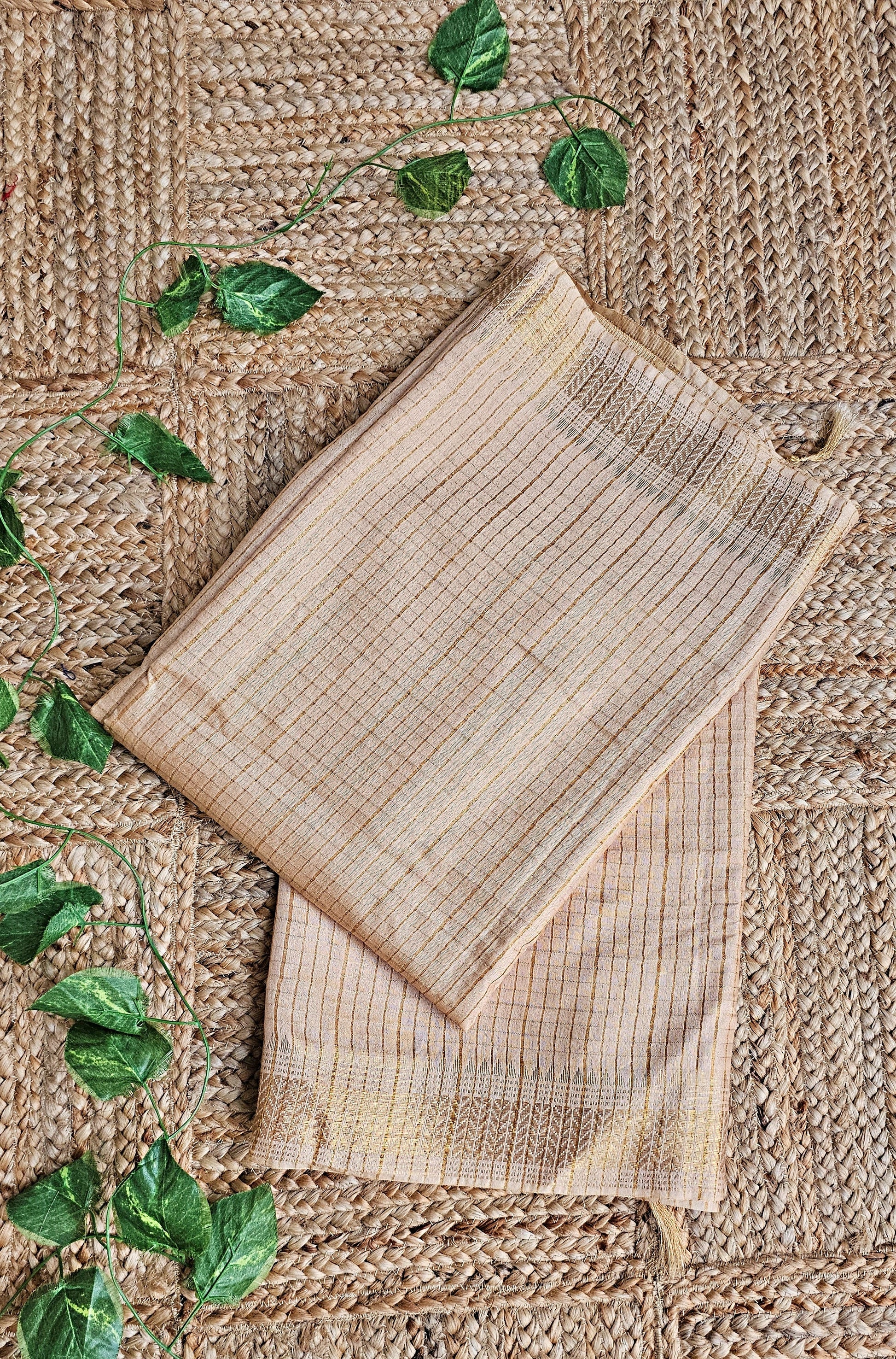 Two woven placemats on a textured surface with green leaves.
